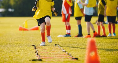 Genç sporcular futbol ekipmanları ile eğitim. Futbol hız eğitim çocuklar için. Genç futbolcu eğitim oturumunda çim futbol sahası üzerinde mavi spor giyim