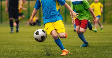 Mavi, sarı ve yeşil mayoyu t-shirt futbol oyunu futbol sahasına tekme. Eylemde çalıştırmayı futbolcular. Gençlik okul futbol maçı. Futbol hakem içinde belgili tanımlık geçmiş.