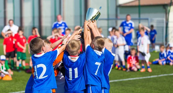 Young Soccer Players Holding Trophy. Boys Celebrating Soccer Football Championship. Winning team of sport tournament for kids children.