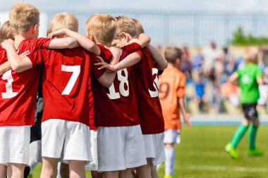 Erkek Futbol Takımı. Çocuk Futbol Akademisi. Futbol oyuncuları kırmızı gömlek birlikte sahada ayakta içinde çocuklar. Gençlik futbol motivasyon konuşması. Genç erkek ile Koç motivasyonel konuşma