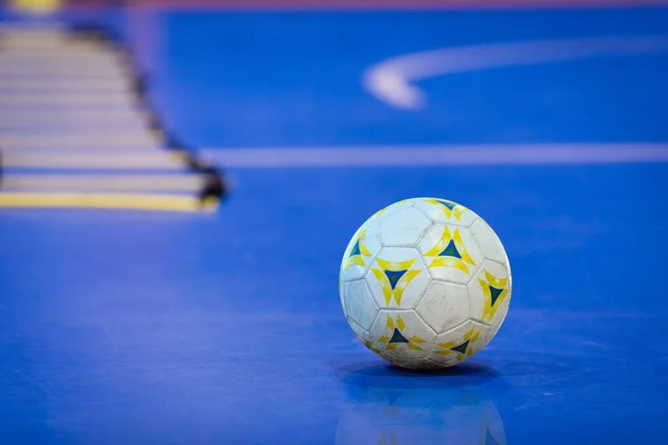 Futsal Ball on Blue Indoor Field. Blue Futsal Training Pitch. Training Agility Ladder in the Background