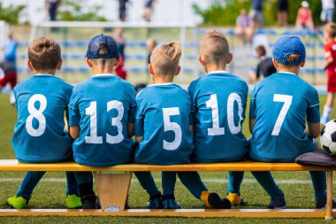 Çocuk futbol takımı maç sırasında. Çocuklar futbol takım üyeleri çim sahada futbol bankta oturmuş. Çocuklar futbol takımı ile saha Stadyumu topa. Çocuk spor futbol takımı