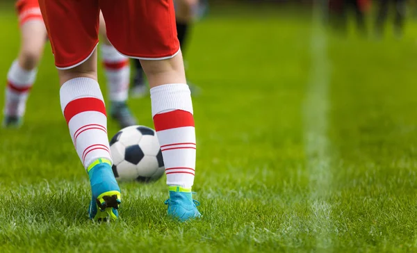详细的足球背景 关闭腿和脚的足球运动员穿着白色的袜子和蓝色的夹板在绿草球场上玩游戏 身穿红色球衣的足球运动员踢足球训练比赛 — 图库照片