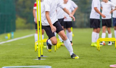 Eğitim Çocuk futbol oyuncusu. Güneşli alanındaki uygulamaları sırasında koni arasında çalışan çocuk. Genç futbolcular hız ve çeviklik oturum pratik