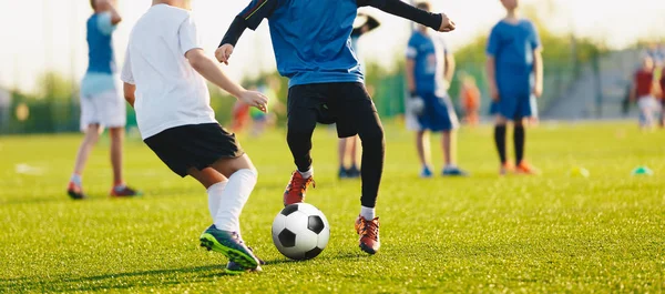 Мальчик пинает футбольный мяч. Крупный план действий мальчиков футбольных команд, в возрасте 8-10, играющих в футбольном матче — стоковое фото