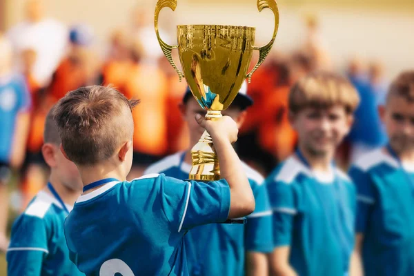 少年は黄金のトロフィーを保持しているチームとのスポーツの成功を祝う — ストック写真