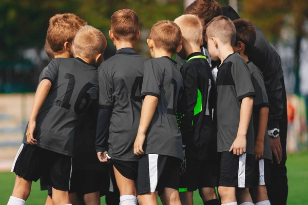 Equipo de fútbol masculino en Huddle. Niños Sport Football Team Reuniéndose con el entrenador en el recinto deportivo —  Fotos de Stock