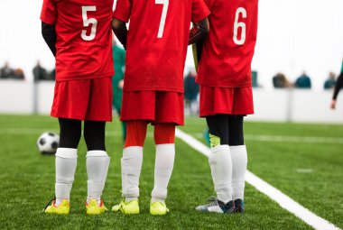 Genç Futbolcular Duvarda Duruyor. Futbol maçı sırasında serbest vuruş durumu. Kırmızı Futbol Formayı Giyen Oyuncular. Futbol Turnuvası Oyunu