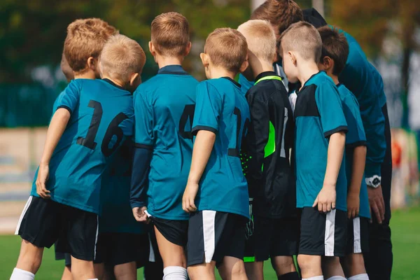 チームハドルのサッカー少年たち。フットボールのコーチとチームのハドルの子供たち。スクールフットボールチーム — ストック写真