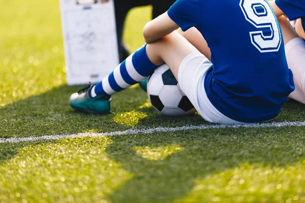 Joven jugador de fútbol durante la sesión de entrenamiento. Niños sentados en el estadio de fútbol verde. Fondo de Entrenamiento de Fútbol. Educación deportiva —  Fotos de Stock