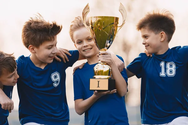 Equipo deportivo de chicos celebrando la victoria. Niños felices sosteniendo trofeo de oro — Foto de Stock