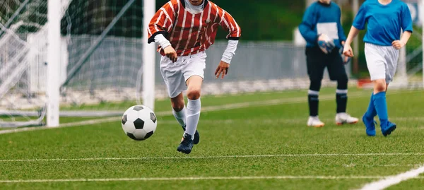 試合中に決闘を実行するジュニアサッカー。ピッチ上のボールの後に走るプレーヤー — ストック写真