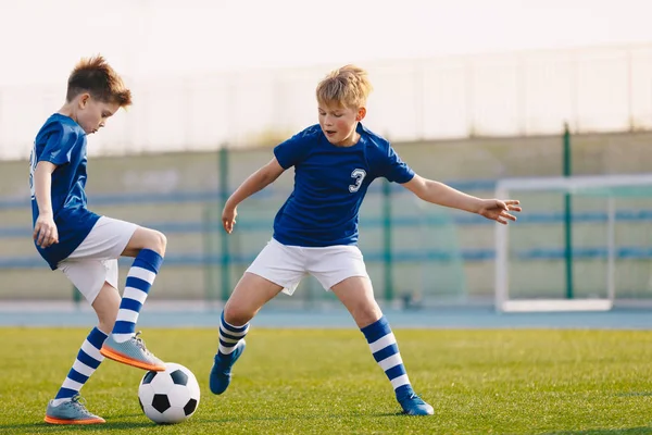 Due giocatori di calcio junior che si allenano con il pallone da calcio sul passo dell'erba dello stadio — Foto Stock
