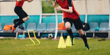 Erkek futbol oyuncusu eğitim. Çocuklar koni arasında çalışan ve Sunny Day alanında uygulama sırasında atlama. Hız ve çeviklik uygulama oturumunda genç futbolcular