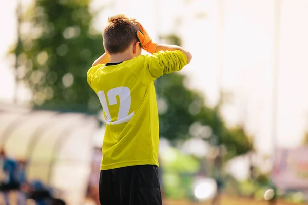 Λυπημένος μικρός τερματοφύλακας ποδοσφαίρου. Απογοητευμένος αγόρι με κίτρινο τερματοφύλακα σετ αθλητικών ρούχων με τα χέρια στο κεφάλι του. Ομάδα ποδοσφαίρου νεαρών εφήβων που χάνει τον στόχο — Φωτογραφία Αρχείου
