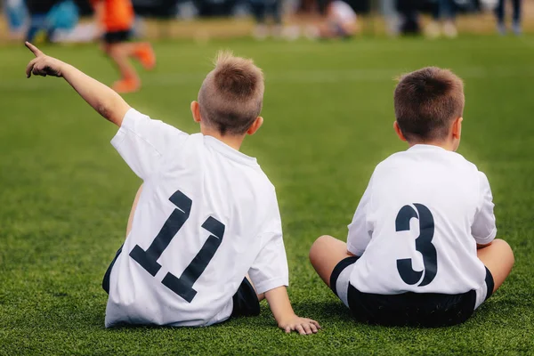 Dois jovens meninos no futebol Sportswear sentado no local da grama — Fotografia de Stock