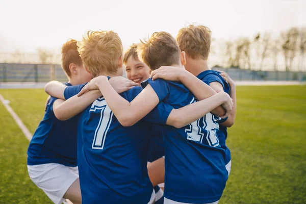 学校のスポーツチームで友人の幸せな子供たちのグループ。男の子が集まって、スポーツフィールドで楽しんでいます。学校サッカーチームの陽気な子供の男の子の選手。ジュニアサッカーチームの幸せな男の子 — ストック写真