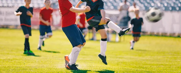 Děti hrají fotbal. Mladí kluci běží a kopat fotbalový míč na travnaté sportovní hřiště — Stock fotografie