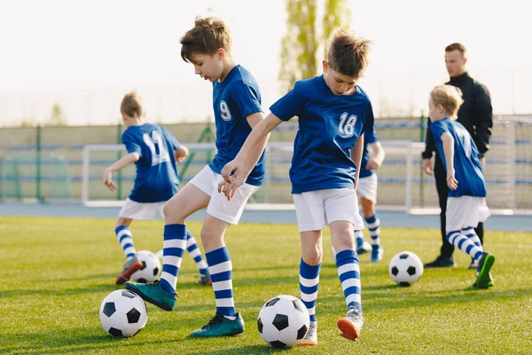Crianças Treinando Futebol no Campo. Jovens meninos chutando bolas de futebol de futebol na grama Pitch. Crianças em Sportswear Prática de Futebol Habilidades — Fotografia de Stock