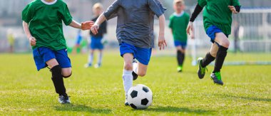 Boy Kicking Futbol Topu. Futbol oyuncuları çalıştırıyor. Düelloda beş genç futbolcu. Arka Planda Futbol Çim Saha ve Futbol Stadyumu.
