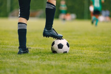 Sahada top oynayan genç bir futbolcu. Spor giysili bir çocuk. Siyah çorap ve krampon giyen bir oyuncu. Futbol yatay kapatma arkaplanı