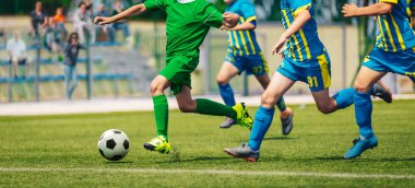 Küçükler düzeyinde futbol yarışması. Okul futbol turnuvası. Rummer gününde top peşinde koşan bir grup çocuk.