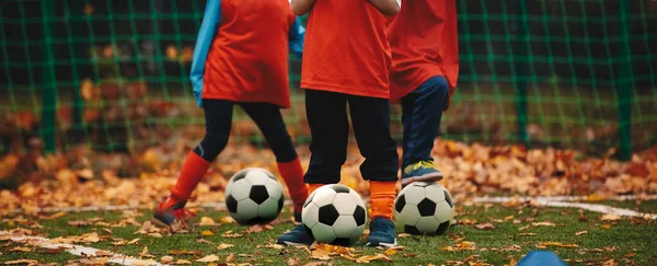 Tres chicos en entrenamiento de fútbol en otoño. Sesión de práctica al aire libre de fútbol de otoño. Jugadores de fútbol con pelota en el campo de hierba cubierto con licencia de otoño — Foto de Stock