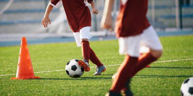 Çocuklar antrenman külahları arasında futbol topları koşuyor. Genç sporcular için Avrupa futbol yaz kampı. Sahada topları olan futbolcular. Arka planda futbol golü ve stadyum