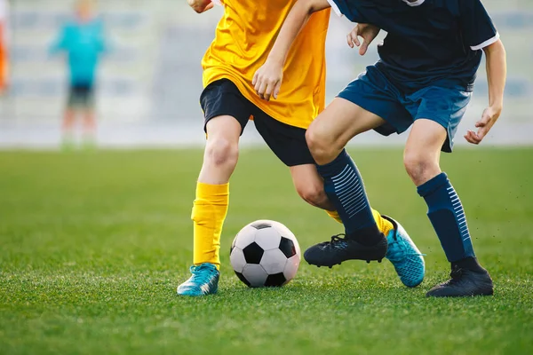 決闘でサッカー選手の足の閉鎖 少年たちは野球場でサッカーボールを蹴った 2人の若いサッカー選手の間の競争の瞬間 — ストック写真