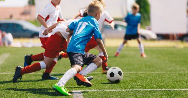 Futbolcular futbol topuyla koşuyor. Okul sporları yarışmasındaki çocuklar. Çocukların futbol turnuvasının yatay görüntüsü