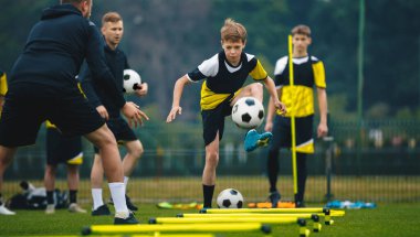 Genç çocuklar iki genç koçla futbol antrenmanında. Antrenman sırasında orta seviye futbolcu topa vuruyor. Engelli futbol antrenmanları çevikliği engeller