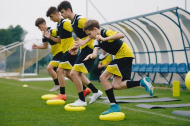 Stabilite Futbol Eğitiminde Denge Yastıklarında Gençler. Spor Dengesi Eğitimi. Genç Futbolcular Çekirdek Gücünü, Dengeyi ve İstikrar Becerilerini Geliştiriyor. Çimen futbol sahası. Futbol koçluğu