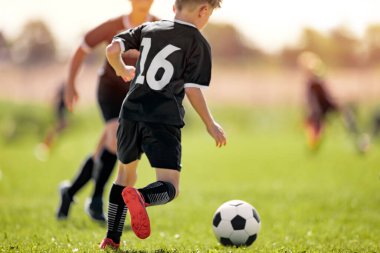 Futbol kulübündeki çocuklar. Okul çocukları için Spor Yaz Eğitim Kampı. Genç Sporcular için Spor Yaz Aktivitesi. Çimenlerde top peşinde koşan çocuk