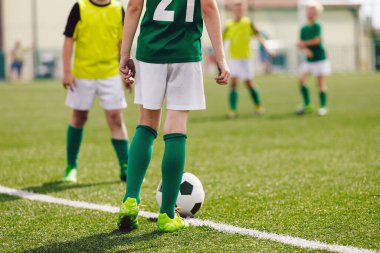 Okul futbol maçı. Çocuklar çim tarlasında futbol topunun peşinden koşuyor. Çocuk sporcular arasındaki spor müsabakası