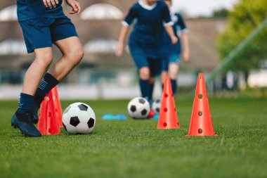 Kozalaklarla antrenman. Futbol kampındaki çocuklar için futbol antrenmanı. Çocuk futbol takımındaki çocuk antrenman yapıyor. Çocuklar futbol topuyla dışarıda antrenman yapıyor. Genç çocuk top sürme yeteneğini geliştiriyor.