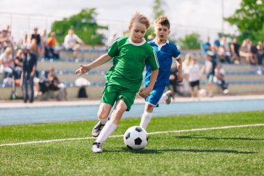 Genç çocuklar futbol oynuyor. Çocuklar sporda eğleniyor. Mutlu çocuklar futbol maçında yarışıyor. Koşan futbolcular. Koşan ve futbol oynayan oyuncular arasındaki rekabet. Futbol okulu.