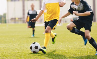Çocuk düelloda futbol topunu tekmeliyor. Koşan futbolcular top için yarışıyorlar. Okul futbol turnuvasına katılan çocuklar
