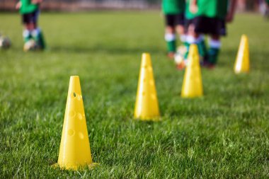 Çocuklar için futbol kampı. Çocuklar tarlada top sürme pratiği yapıyor. Oyuncular iyi top sürme becerileri geliştirirler. Çocuklar top ve külahlarla antrenman yapıyor. Futbol slalom tatbikatı top sürmeyi geliştirir.