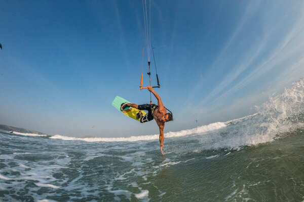 professional kite surfer performing acrobatic trick while rides waves