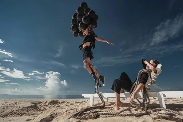 Glückliche Frau Die Mit Schwarzen Luftballons Einem Sandstrand Springt Und — Stockfoto