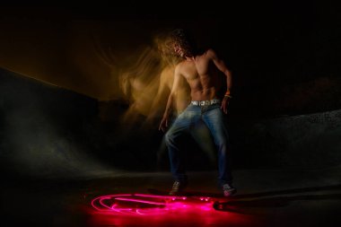 Gece de bir ollie atlama yapıyor bir genç beyaz beyaz kaykaycı