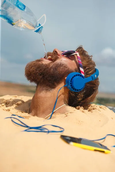 Tipo Con Auriculares Enterrados Arena Bebiendo Agua Botella Sobre Cabeza — Foto de Stock