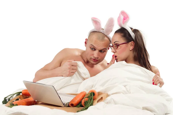 ベッドに横になっていると ノート パソコンを見ているウサギの衣装で素敵なカップル — ストック写真