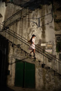 Güzel Sportif sarışın genç kadın elbise ve şapka enjoing binanın üstüne yaz gününde uygun.