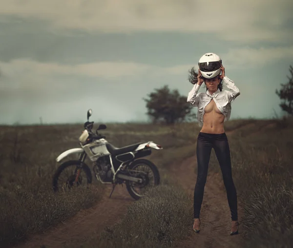 Chica motociclista junto a una motocicleta — Foto de Stock