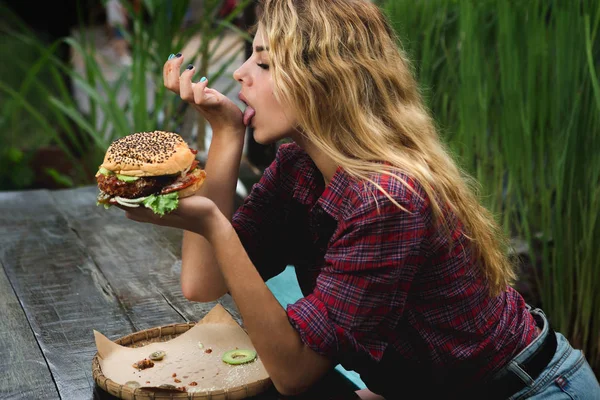 Lány étkezési hamburger a kertben — Stock Fotó