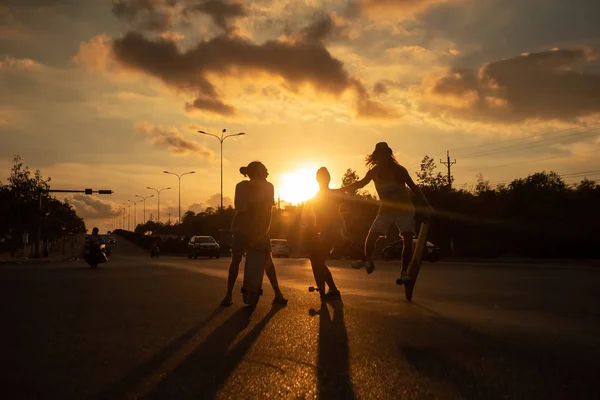 Happy kateboarders ride skateboard at golden sunset — Stock Photo, Image