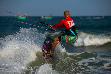 Mui Ne sahilindeki dalgalarda uçurtma uçurmak, Phan Thiet, Binh Thuan, Vietnam. Uçurtma uçurma, Kiteboard aksiyon fotoğrafları. Uçurtma Vietnam gemilerine karşı eylem halinde