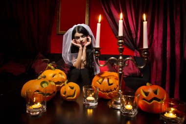 Kırmızı arka planda Cadılar Bayramı balkabakları olan güzel seksi kadın.