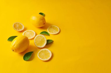 Limonlar ve yeşil yapraklar parlak sarı arka planda. Yemek konsepti, düz konum. Limon meyvesi, narenciye minimum konsept, C vitamini limon ve yapraktan yapılmış yaratıcı arka plan..